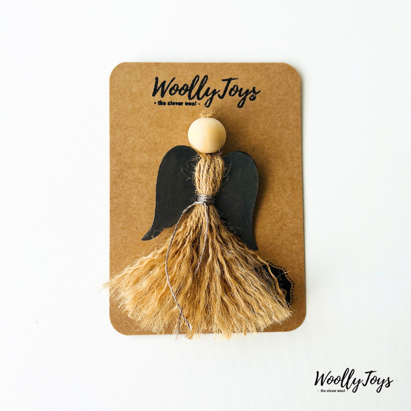 Egy kézműves natúr angyal karácsonyfadísz ezüst szárnnyal, spárgából és fából, elegáns kraft csomagoláson, készen az ajándékozásra.